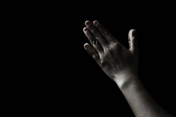 istock praying woman hand in the dark ( praying in secret room concept ) 687915970