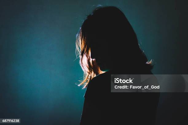 Silhouette Of Depress Woman Standing In The Dark With Light Shine Behind Stock Photo - Download Image Now