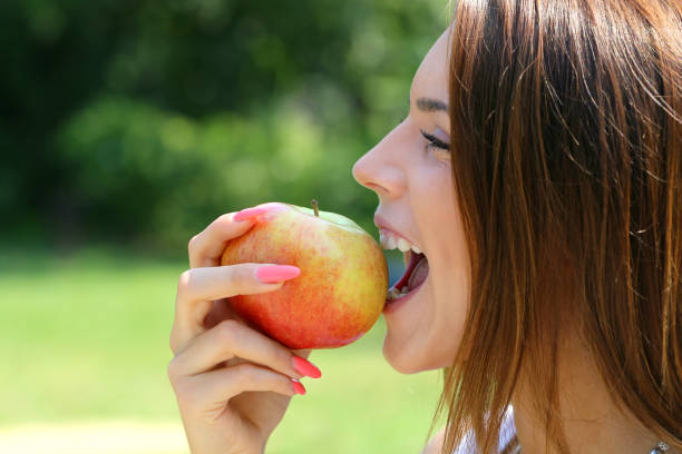 istock young woman bite apple in a park in summer 687917028