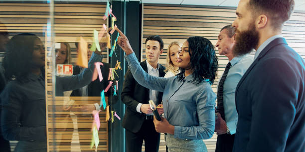 Creative group of business people Creative group of business people brainstorming putting sticky notes on glass wall in office together for yes stock pictures, royalty-free photos & images
