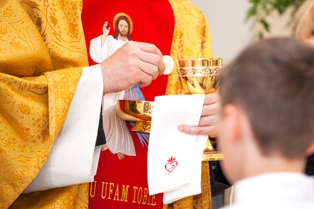 Priest gives first communion. Symbol of the body and blood of Christ. Priest gives first communion. Symbol of the body and blood of Christ. priest photos stock pictures, royalty-free photos & images