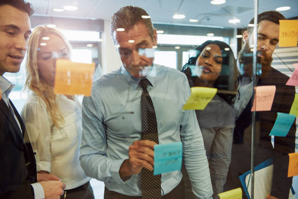 istock Group of business people brainstorming, using posters on wall 687920100