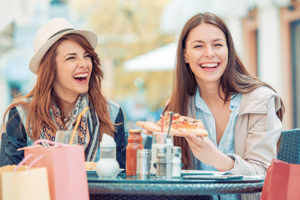 istock Two smiling girls eating pizza in cafe 687924662