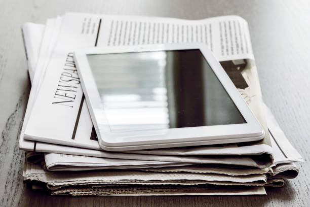 Newspaper and digital tablet on wooden table