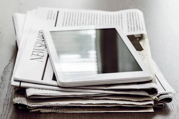 Photo of Newspaper and digital tablet on wooden table