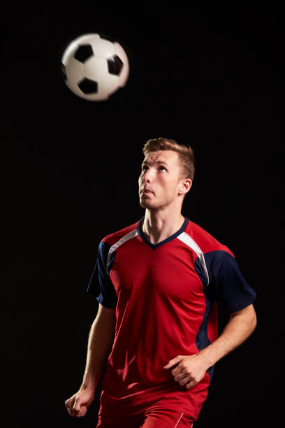istock Professional Soccer Player Heading Ball In Studio 687946322