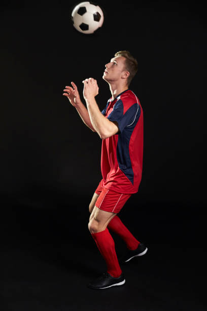 istock Professional Soccer Player Heading Ball In Studio 687946424