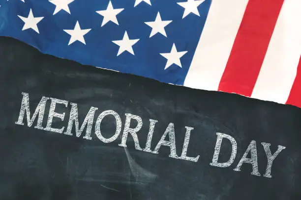 Closeup of United States flag with text of memorial day on the blackboard