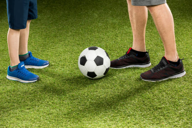 istock partial view of father and son playing soccer on grass 687950826