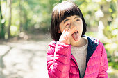 Girl having sticking out tongue in outdoors.
