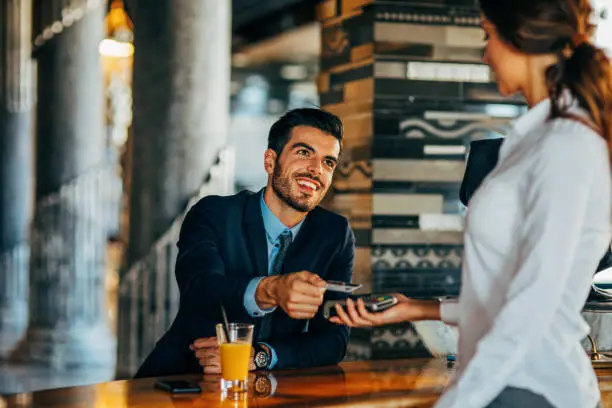 Businessman paying via credit card at a bar counter.