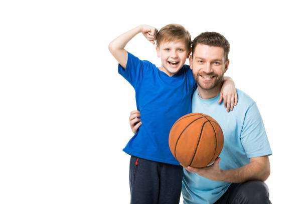 père et enfant de sourire prêt à jouer au basket-ball. garçon affichant ses biceps d'isolement sur le blanc - basketball ball sport isolated photos et images de collection