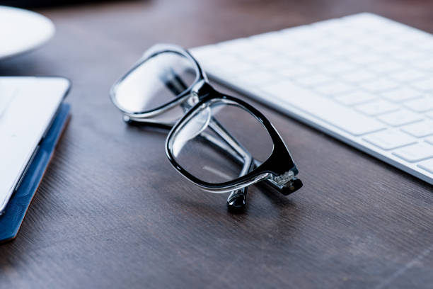 istock eyeglasses near keyboard on wooden table 687958032