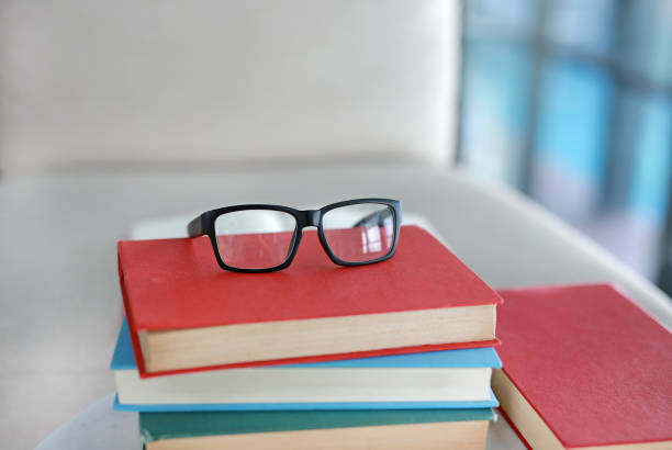 istock Stack of textbooks on desk with glasses on the top in library room, Education concept background. 687959880