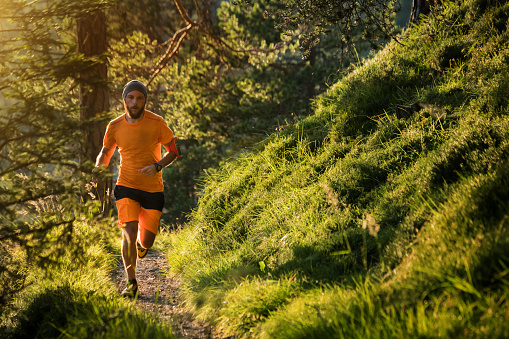 Man trail running in the forest up mountain