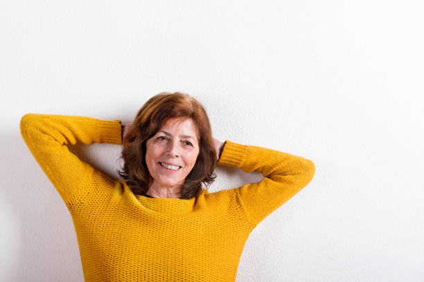 istock Senior woman in yellow woolen sweater, studio shot. 687976632