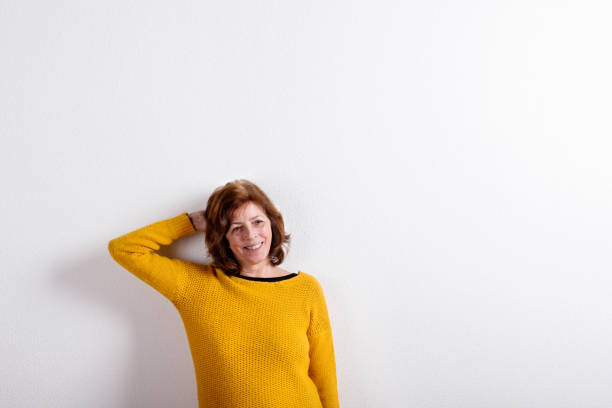 istock Senior woman in yellow woolen sweater, studio shot. 687976940