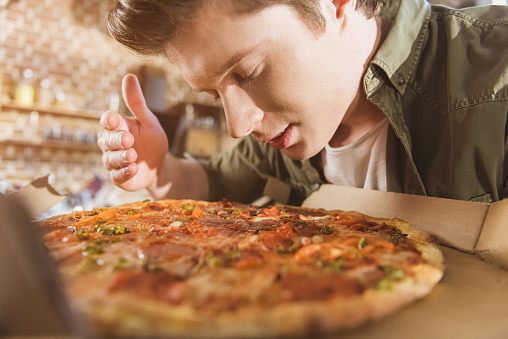 young man enjoying smell of fresh hot pizza