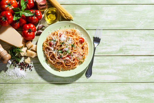 pastateller und zutaten auf grüne küchentisch - italian culture ingredient spaghetti food stock-fotos und bilder