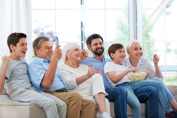 istock Excited family watching television on sofa 688008802