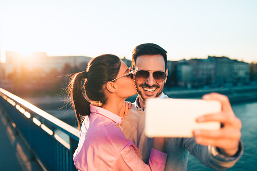 Image of a smiling couple on bridge taking Selfie. Copy space.