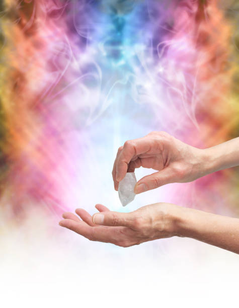Crystal healer sensing energy with terminated quartz Crystal Healer holding terminated quartz in one hand pointing it at open palm with psychedelic rainbow coloured energy formation in background chakra recovery energy gem stock pictures, royalty-free photos & images