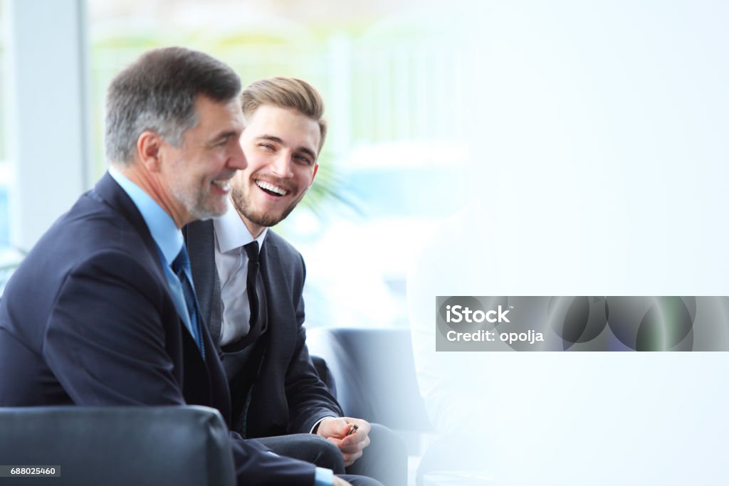 Mature businessman using digital tablet to discuss information with a younger colleague in a modern business lounge Mature businessman using a digital tablet to discuss information with a younger colleague in a modern business lounge Two People Stock Photo
