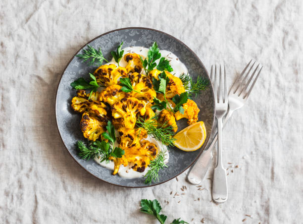 coliflor de cúrcuma asada con aderezo de yogur griego. deliciosa comida sana sobre un fondo gris, vista superior - cauliflower roasted parsley cooked fotografías e imágenes de stock