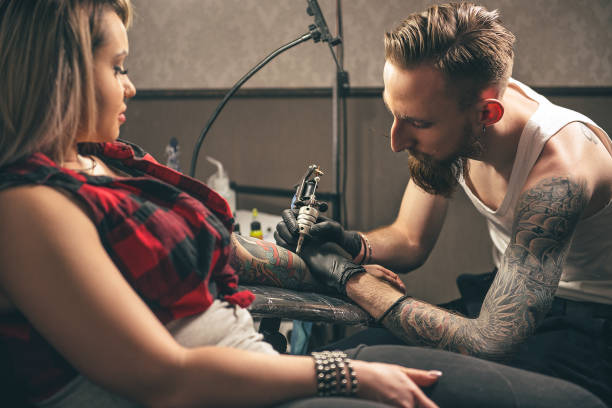 istock Serene man making tattoo on woman hand 688034000