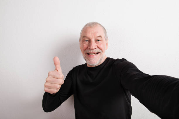 istock Senior man in black woolen sweater, thumb up, studio shot. 688046212