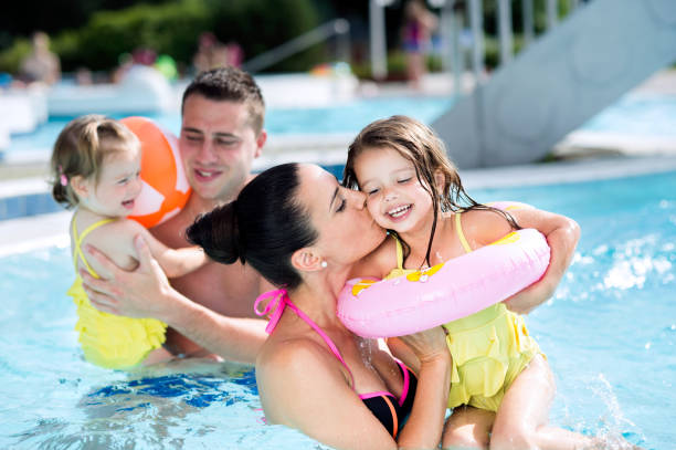 istock Mother, father and daughters in swimming pool. Sunny summer. 688051808
