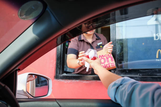 клиент, получающий гамбургер и мороженое после заказа и купить его от mcdonald's диск через обслуживание - bangkok mcdonalds fast food restaurant asia стоковые фото и изображения