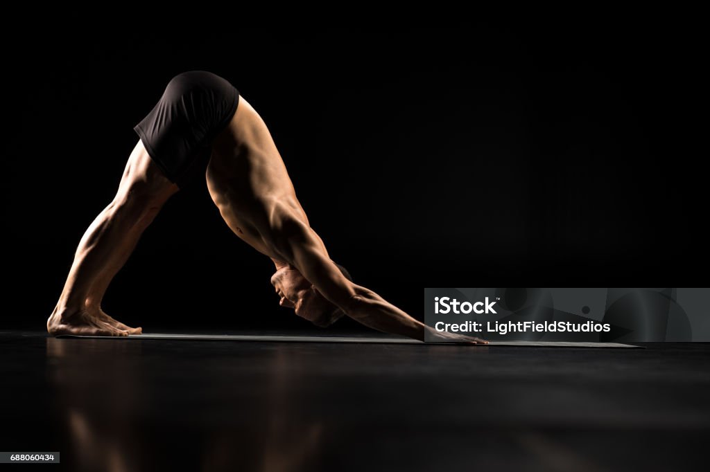 Man standing in yoga position Man performing Adho Mukha Svanasana or Downward Facing Dog Pose Active Lifestyle Stock Photo
