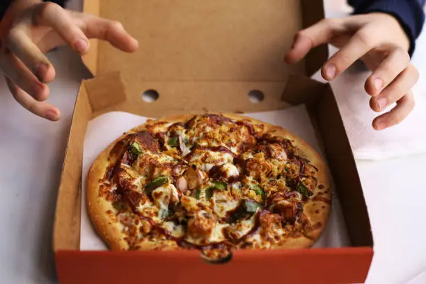 Photo of kid hands grab pizza in cardboard box