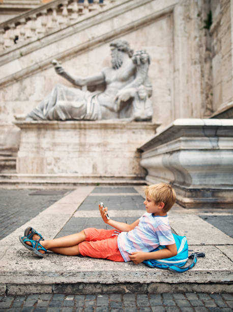 poco turista niño descansando en la piazza del campidoglio, roma, italia - fontana della dea roma fotografías e imágenes de stock