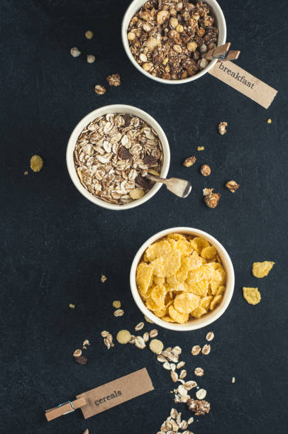 завтрак зерновых в бумажных стаканчиках на темном бетонном фоне. диета или концепция здорового питания - vertical ramp стоковые фото и изображения