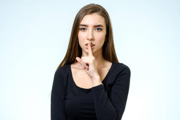 istock Keep silence! Beautiful young woman holding finger on lips and looking at camera isolated on white 688107334