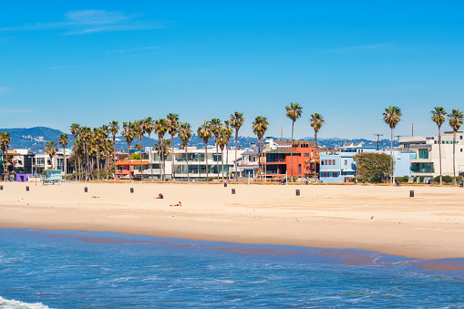 Stock photograph of beach and row of waterfront homes in Venice Beach, Los Angeles, California, USA on a sunny day.
