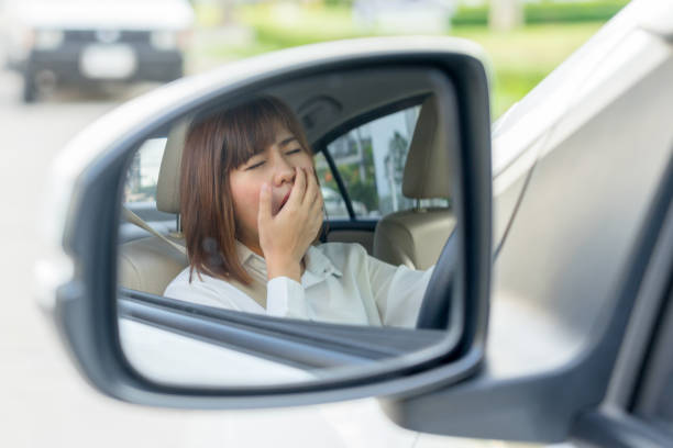 Closeup portrait sleepy, tired young woman driving her car after long hour trip in mirror, Sleep deprivation, accident concept. stock photo