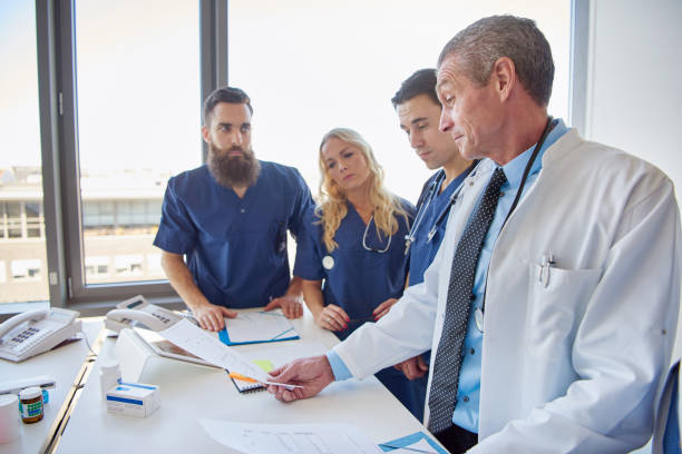 istock Team of doctors looking at papers while briefing 688132960