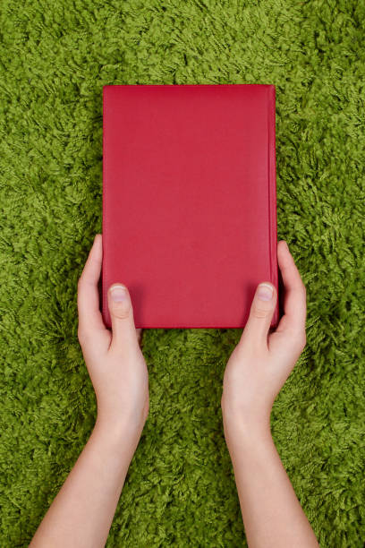 istock Woman's hands holding a red  book isolated on green background. 688143696