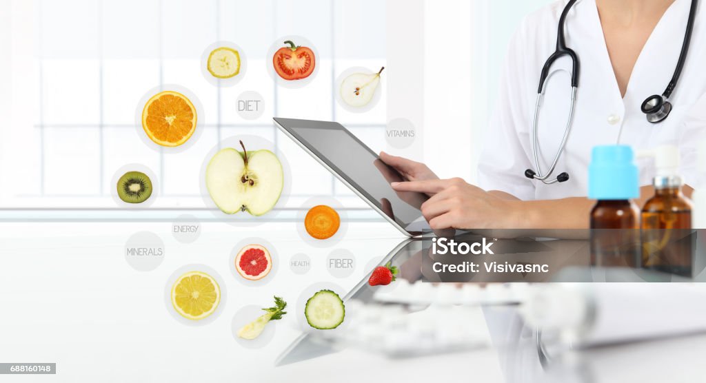 healthy food supplements concept, Hand of nutritionist doctor touch digital tablet on symbols fruits background Medical Exam Stock Photo