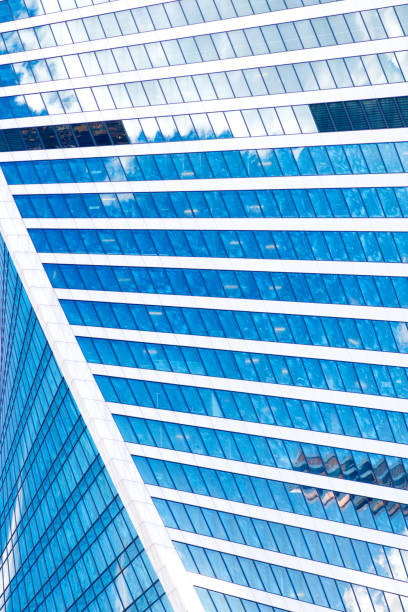 istock Abstract skyscrapers with reflection in windows blue sky, white clouds and sun glare 688191584