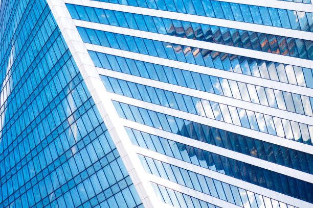 istock Abstract skyscrapers with reflection in windows blue sky, white clouds and sun glare 688205792