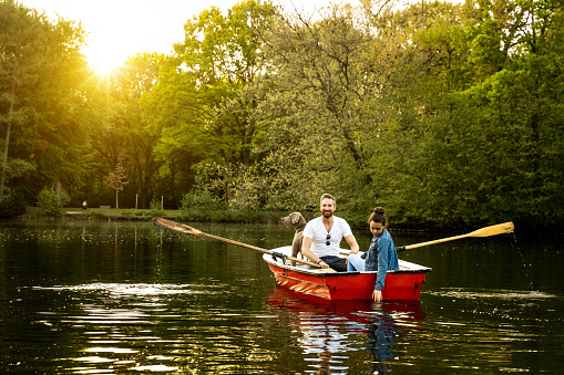 Father, daughter and dog in rowboat on lake