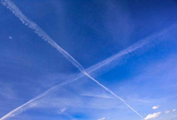 ciel de printemps bleu avec des traces en forme de x d’aéronefs - fighter plane photos et images de collection