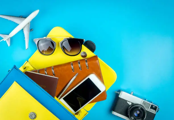 Photo of Women purse with travel accessories with toy plane on blue background