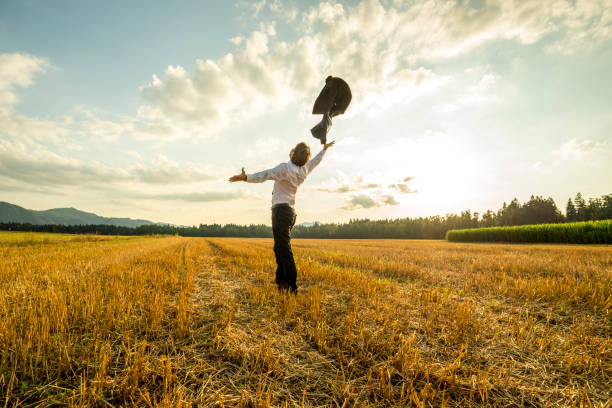 Businessman in field throwing jacket in air stock photo