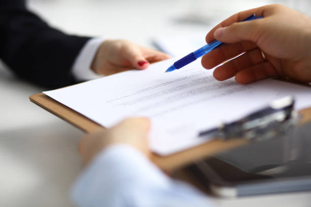 Close up of an executive hands holding a pen and indicating where to sign a contract at office Close up of an executive hands holding a pen and indicating where to sign a contract at office. witness signature stock pictures, royalty-free photos & images
