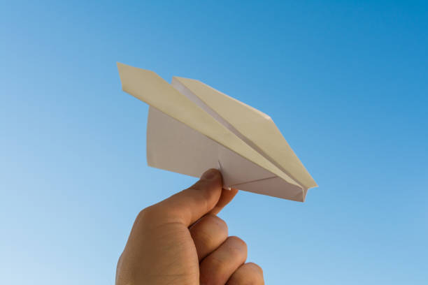 istock Hand holds white paper plane on blue sky 688238918